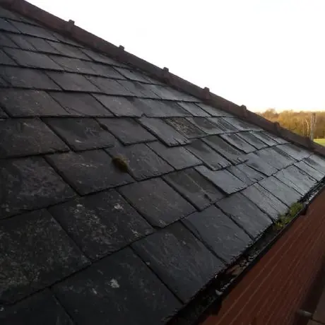 Roofing in Atherton: weathered slate roof edge meeting a brick gable
