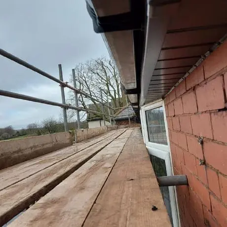 Roofing near Golborne: new fascia and soffit boards along a brick wall with scaffolding