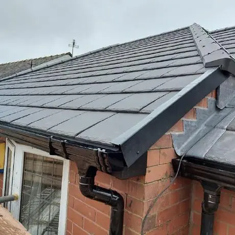 Roofing near Atherton: new roof ridge with black guttering and downpipe