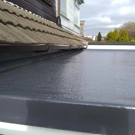 flat roofing in Wigan: grey GRP flat roof edge beside a tiled roof